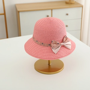 Detailed view of pink straw sun hat with polka dot ribbon and bow on a metal stand