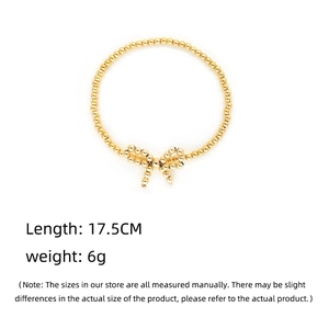 Dettaglio di un bracciale dorato con perline e fiocco, lunghezza 17,5 cm e peso di 6 g
