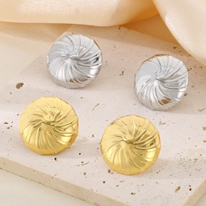 Elegante goldene und silberne Ohrstecker mit Spiralstruktur auf Steinplatte