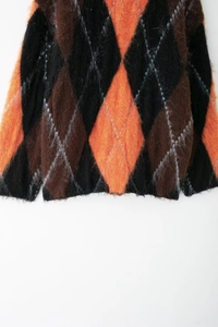 Détail de la texture d'un pull en tricot à losanges noir orange et marron d'Halloween