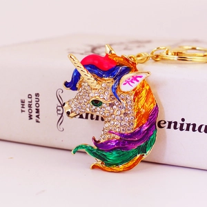 Golden unicorn keychain with colorful enamel mane and rhinestones on a book