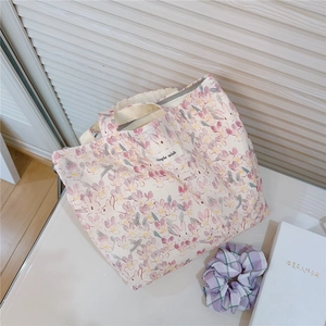 Detail of pink floral canvas tote bag with white label and gray zipper closure