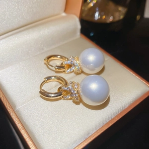 Vue macro de boucles d'oreilles perles plaquées or avec nœud en zircon scintillant