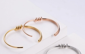 Detailed view of knotted titanium steel bangles in gold, rose gold and silver finishes