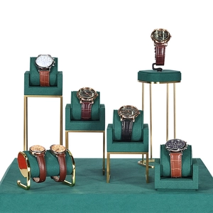 Golden metal watch display set with dark green velvet pillows in tiered arrangement