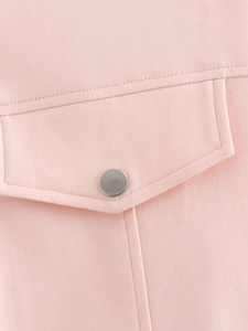 Détail de la poche de veste varsity rose avec tissu sergé et bouton métallique argenté