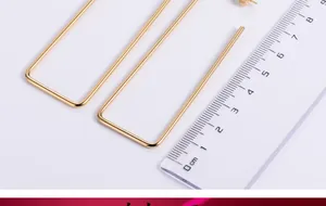 Detail view of gold rectangular hoop earrings with a ruler showing dimensions