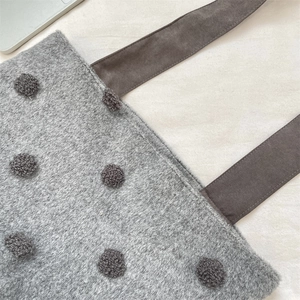 Dettaglio borsa tote in feltro grigio con pois 3D e tracolla in tessuto marrone
