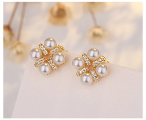 Detailed view of flower-shaped pearl earrings with gold base and sparkling zircon accents