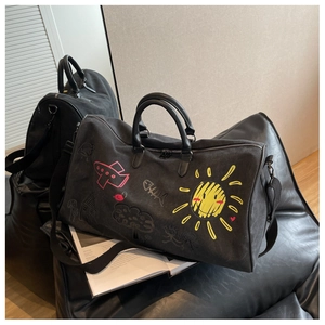 Detail shot of black travel bag with colorful hand-drawn graffiti patterns on a sofa