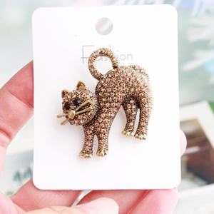 Macro detail of cat brooch featuring amber rhinestones and vintage gold metal finish