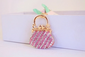 Detailed macro view of gold-tone mini handbag charm with pink and white rhinestones
