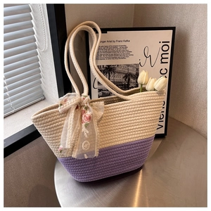 Close-up of woven tote bag with purple accents, floral ribbon and white tulips on a table