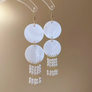 Detailed view of bamboo shell earrings with small pearl tassels and golden accents