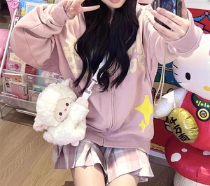 Detail of a white plush sheep crossbody bag paired with a pink hooded sweatshirt