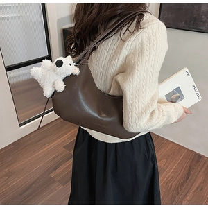 Close-up of sleek dark brown PU leather shoulder bag with a white plush doll charm accessory