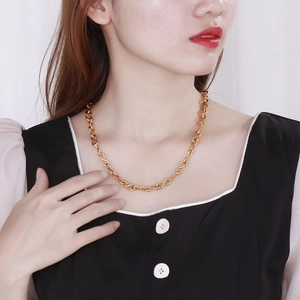 Close-up of golden infinity link necklace worn by a model in black and white attire
