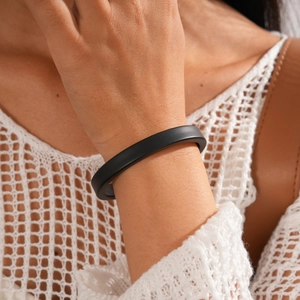 Close-up of a minimalist matte black irregular acrylic cuff bangle worn on the wrist