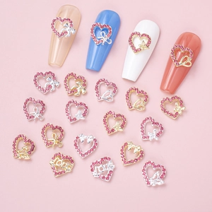 Close-up of pink heart-shaped nail charms with hollow bow and glitter rhinestones