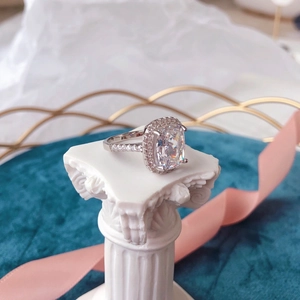 Detailed macro view of S925 silver halo ring with cushion cut zircon on white pedestal