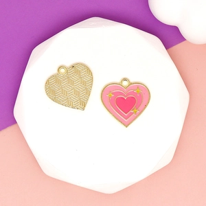 Detail view of pink enamel heart charms with golden borders and star pattern for DIY crafts