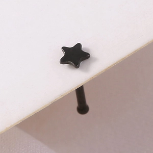 Macro shot of a black star-shaped stainless steel nose stud on a white display card