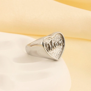 Detail view of silver heart signet ring with Mom text and textured diamond pattern