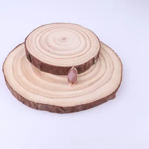 Detail of copper wire wrapped rectangular natural pink stone pendant on wood chips
