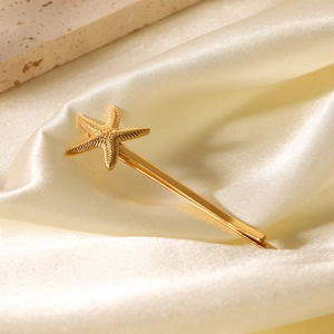 Barrette étoile de mer dorée élégante posée sur un fond luxueux en tissu de soie