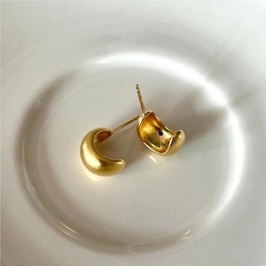 Detailed view of U-shaped gold earrings with matte brushed and polished finishes