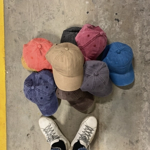 Classic washed cotton baseball caps in multiple colors stacked on urban concrete surface