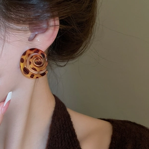Close-up of leopard pattern resin spiral earrings worn by a model in a trendy retro style