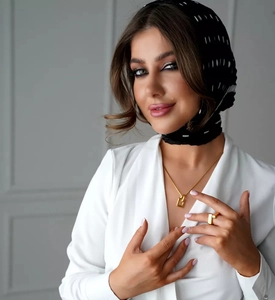 Close-up of elegant gold square pendant necklace and matching ring on model with headscarf