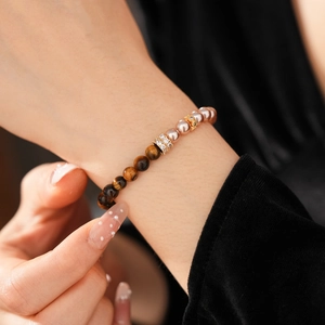 Macro shot of tiger eye beads and pearls on a stretch bracelet with gold accents