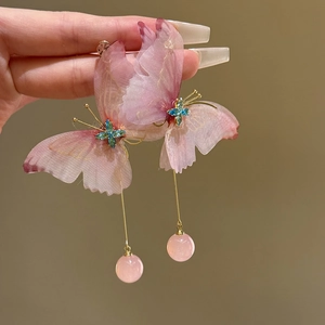 Detailed view of pink fabric butterfly earrings with long gold tassels and beads