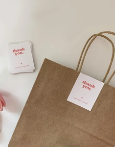 Detail of Thank You stickers and cards on a brown kraft paper gift bag with tulips