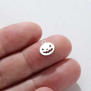 Silver Halloween pumpkin charm pendant for DIY jewelry making shown on finger for scale