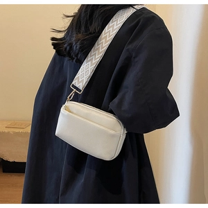Detail of cream PU leather crossbody bag with geometric pattern wide woven strap