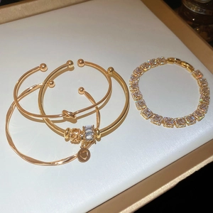 Détail de bracelets nœuds dorés et d'un bracelet tennis serti de zircons cubiques