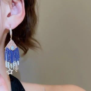 Macro shot of Bohemian beaded fringe earrings with blue gemstones and gold star charms