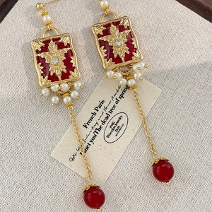French vintage earrings with red enamel flower, pearls and golden tassels on fabric
