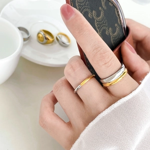 Two-tone stainless steel rings with minimalist oval and star designs on female hand