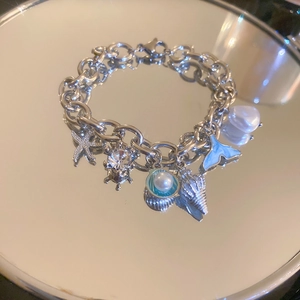 Macro detail of silver ocean charm bracelet with starfish, pearls and shells