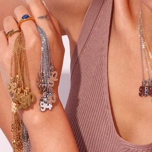 Detail view of 18K gold plated year necklaces and gemstone rings on model skin