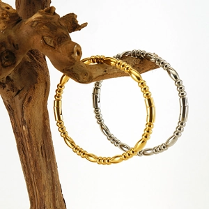 Minimalist gold and silver titanium steel bead bracelets on rustic wood display