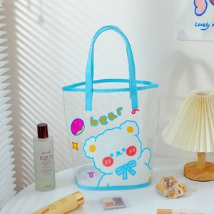 Detail of transparent PVC cartoon tote with mesh bottom and blue trim in sunlight