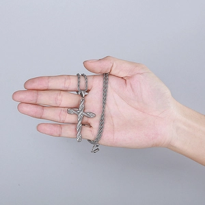 Nahaufnahme des silbernen Edelstahl-Kreuzanhängers mit Kordelkette auf der Hand
