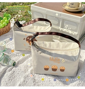 Detail view of two large insulated lunch bags with cute muffin patterns in a picnic setting