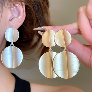 Detail view of large geometric brushed metal earrings in silver and gold minimalist design