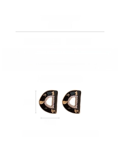 Detailed view of D-letter earrings with black gold finish and sparkling zircon inlays